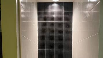 Un baño pequeño y moderno con inodoro, secador de manos y cubo de basura.
