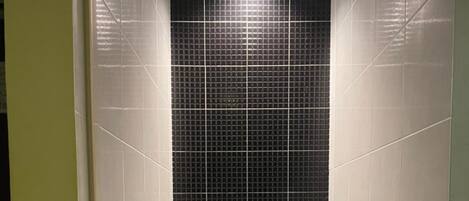 Un baño pequeño y moderno con inodoro, secador de manos y cubo de basura.