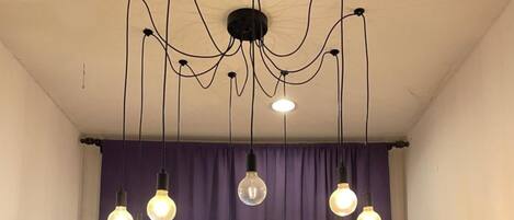 A room with a ceiling light fixture and hanging pendant lights.