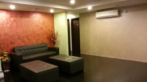 A lobby with a sofa, ottoman, and a small table. - Zotel Hotel (Kuching)