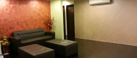 A lobby with a sofa, ottoman, and a small table.