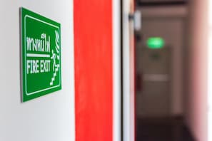 Un panneau vert indiquant la sortie de secours, fixé au mur.