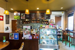 L’intérieur d’un café, avec un tableau affichant le menu, un espace pour s’asseoir et une vitrine.