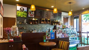 Un café chaleureux avec des banquettes en bois, des suspensions décoratives et un tableau affichant le menu.