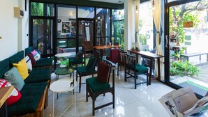 Un intérieur moderne avec un canapé, des fauteuils, une petite table et une grande fenêtre donnant sur un paysage verdoyant.