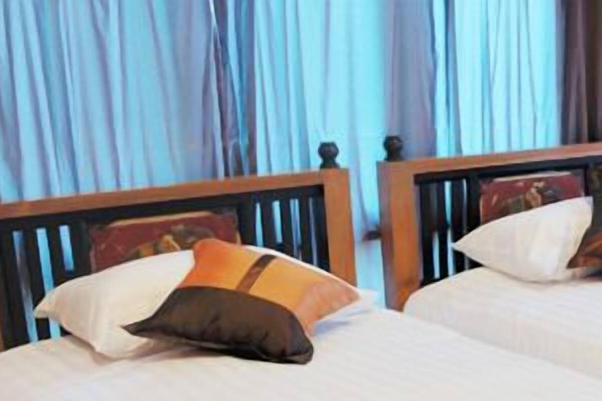 Two single beds with wooden headboards, white linens, and colorful pillows.
