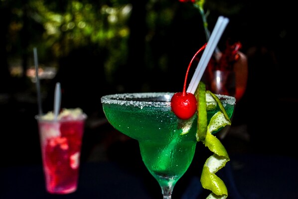 A martini glass with a green liquid, a red cherry, and a lemon twist garnish. - Termales del Bosque & Hot Springs (Quesada)