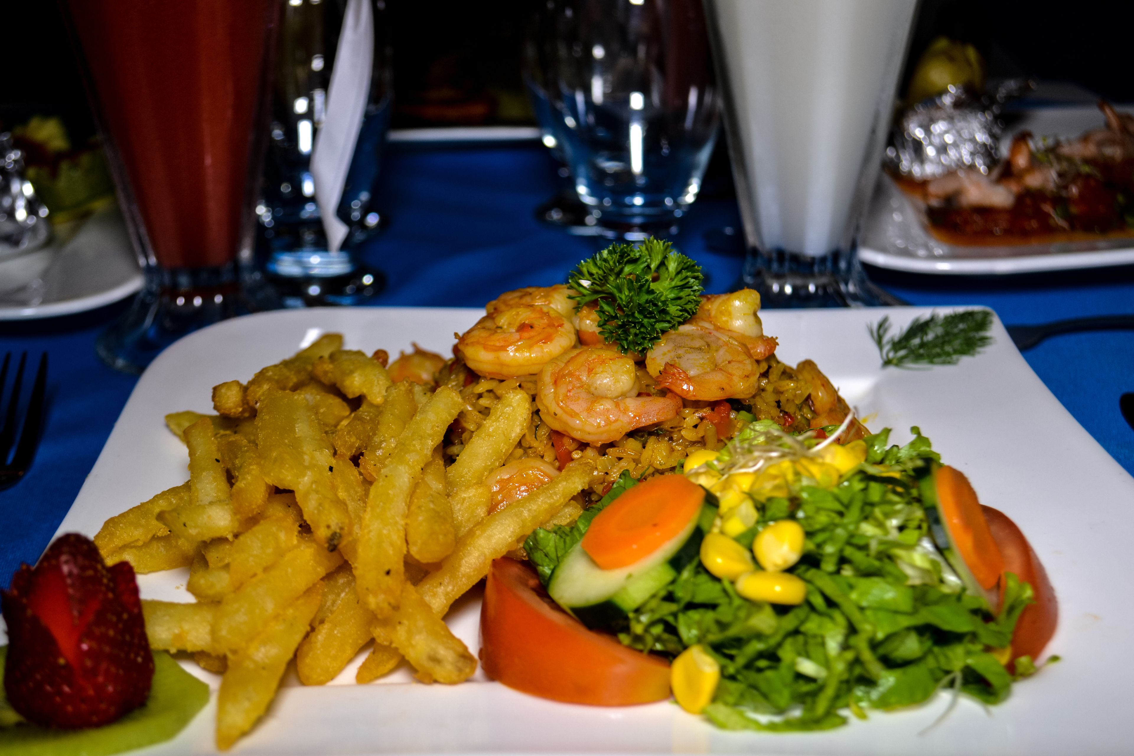 A plate of food with shrimp, fries, and a salad.