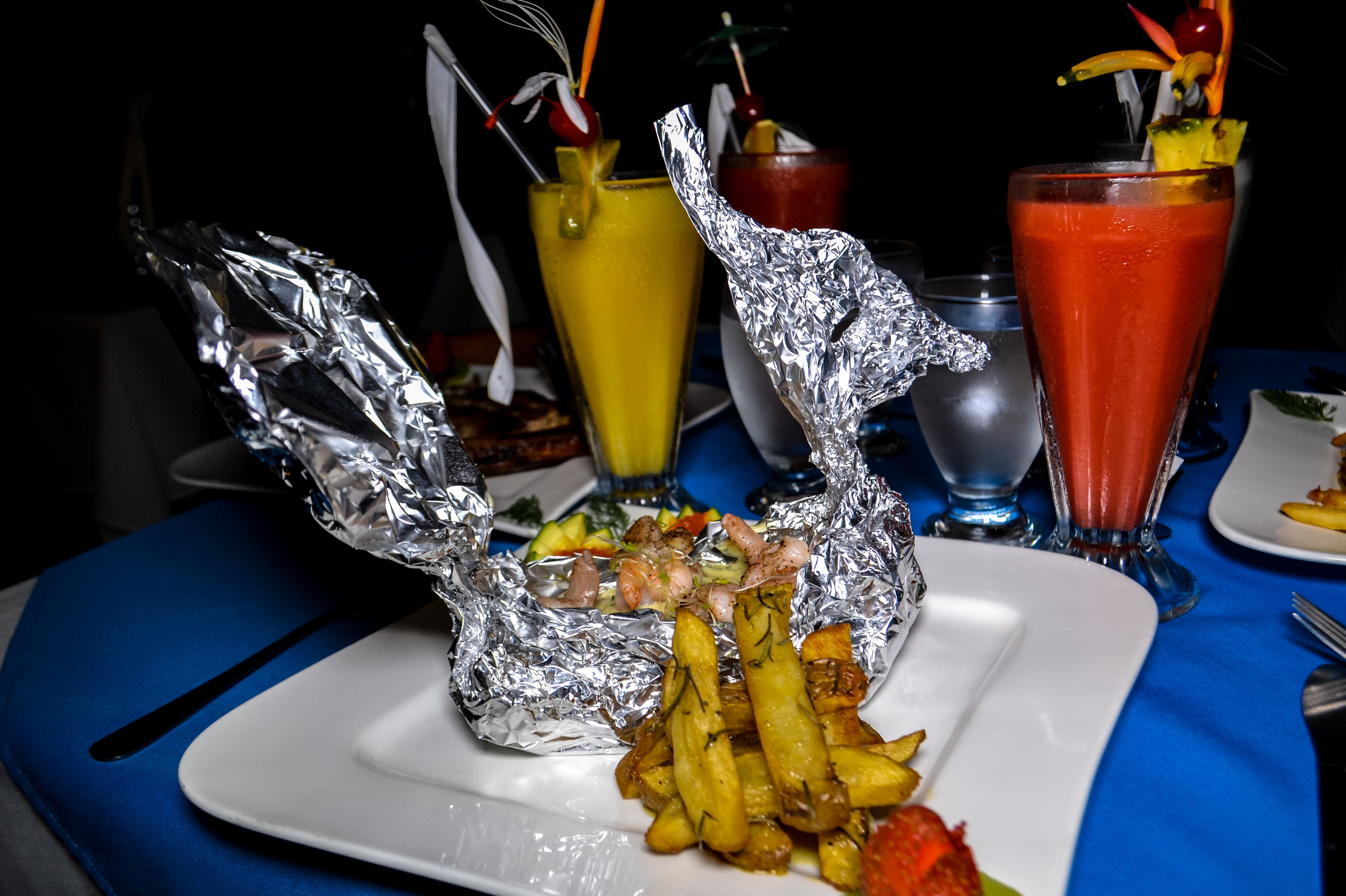 A plate with food and drinks on a table with a blue tablecloth.