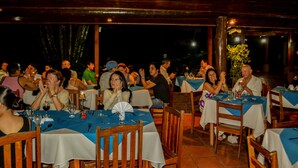 Un área de comedor al aire libre con varias mesas y sillas, cubierta por un techo de madera.