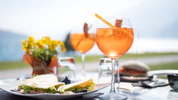 Un tavolo con un panino, una bevanda in un bicchiere e un piccolo vaso con fiori.