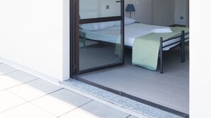 A room with a bed, a radiator, and a hanging coat rack. - Lake Como Beach Hostel (Domaso)