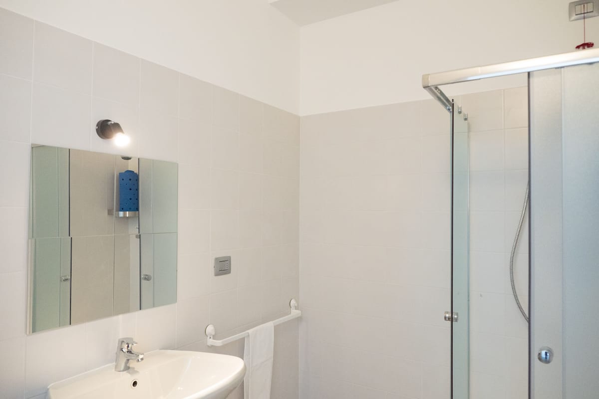A bathroom with a sink, mirror, and glass shower enclosure.