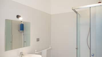 Un baño con lavabo, espejo y cabina de ducha de vidrio.