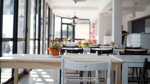 A modern dining area with large windows, wooden tables, and chairs. - Lake Como Beach Hostel (Domaso)