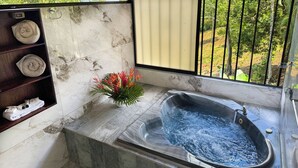 A bathroom with a marble sink, a bathtub, and a shelf with towels. - Hotel Heliconias Nature Inn & Hot Springs (Peñas Blancas)