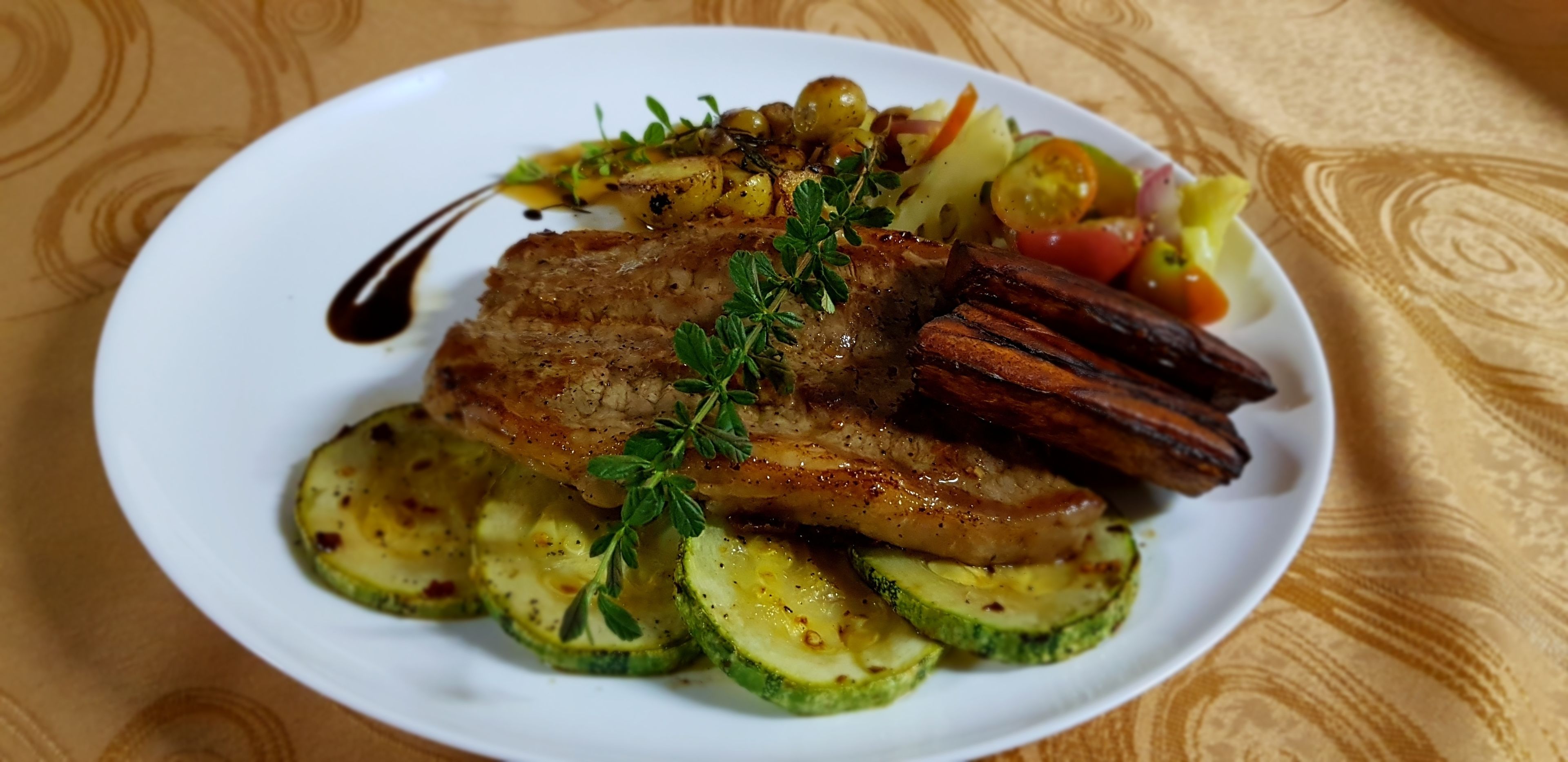 A plate of food with grilled meat, zucchini slices, and vegetables.