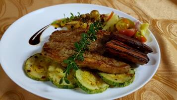 A plate of food with grilled meat, zucchini slices, and vegetables.