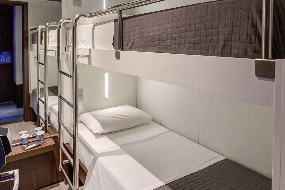 Ein Hotelzimmer mit Stockbetten, einem Schreibtisch und einem Stuhl sowie einem Fernseher.