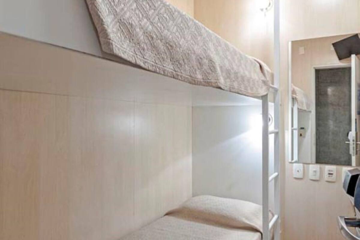 Ein Schlafzimmer mit Etagenbetten, einem Spiegel und einem kleinen Waschbecken.