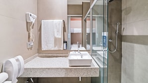 Une salle de bain moderne équipée d’un lavabo, d’un miroir, d’un porte-serviettes et d’une cabine de douche en verre.