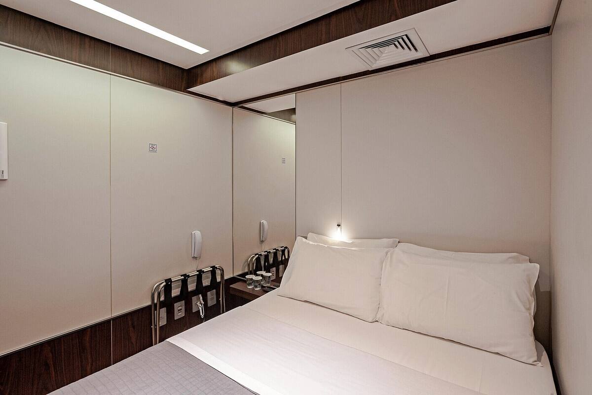Ein Hotelzimmer mit einem großen Bett, einem Nachttisch, einem Spiegel und einem Kleiderschrank.