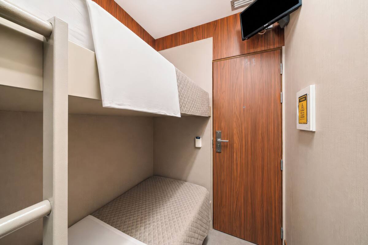 Ein Schlafraum mit Etagenbetten, einer Holztür und einem Thermostat an der Wand.