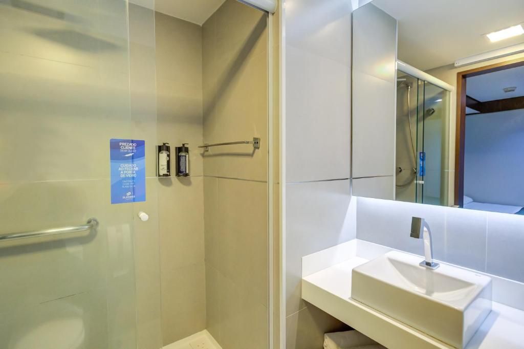 A modern bathroom with a glass-enclosed shower, a white sink, and a mirror.