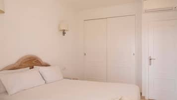 A bedroom with a bed, a nightstand, a lamp, and a wardrobe.