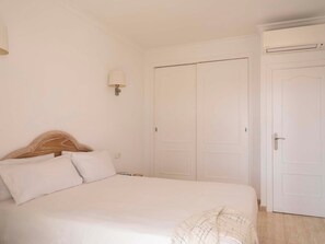 A bedroom with a bed, a nightstand, a lamp, and a wardrobe. - Ona Village Cala d'Or (Santanyi)