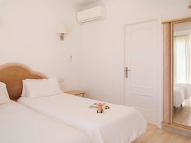 Habitación de hotel con dos camas, una mesita de noche, una lámpara, un equipo de aire acondicionado y un espejo.