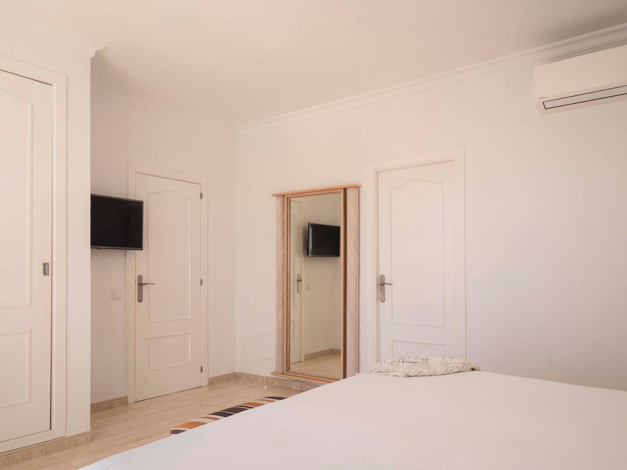 A bedroom with a bed, a television, and two doors.