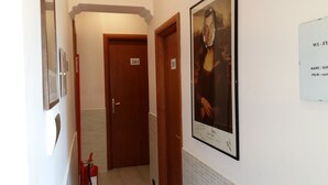 A hallway with doors numbered 203 and 201, a fire extinguisher, and a framed artwork on the wall. - SunMoon (Rome)