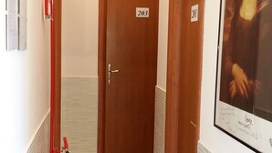 A corridor with doors numbered 203 and 201, a fire extinguisher, and a framed artwork on the wall. - SunMoon (Rome)