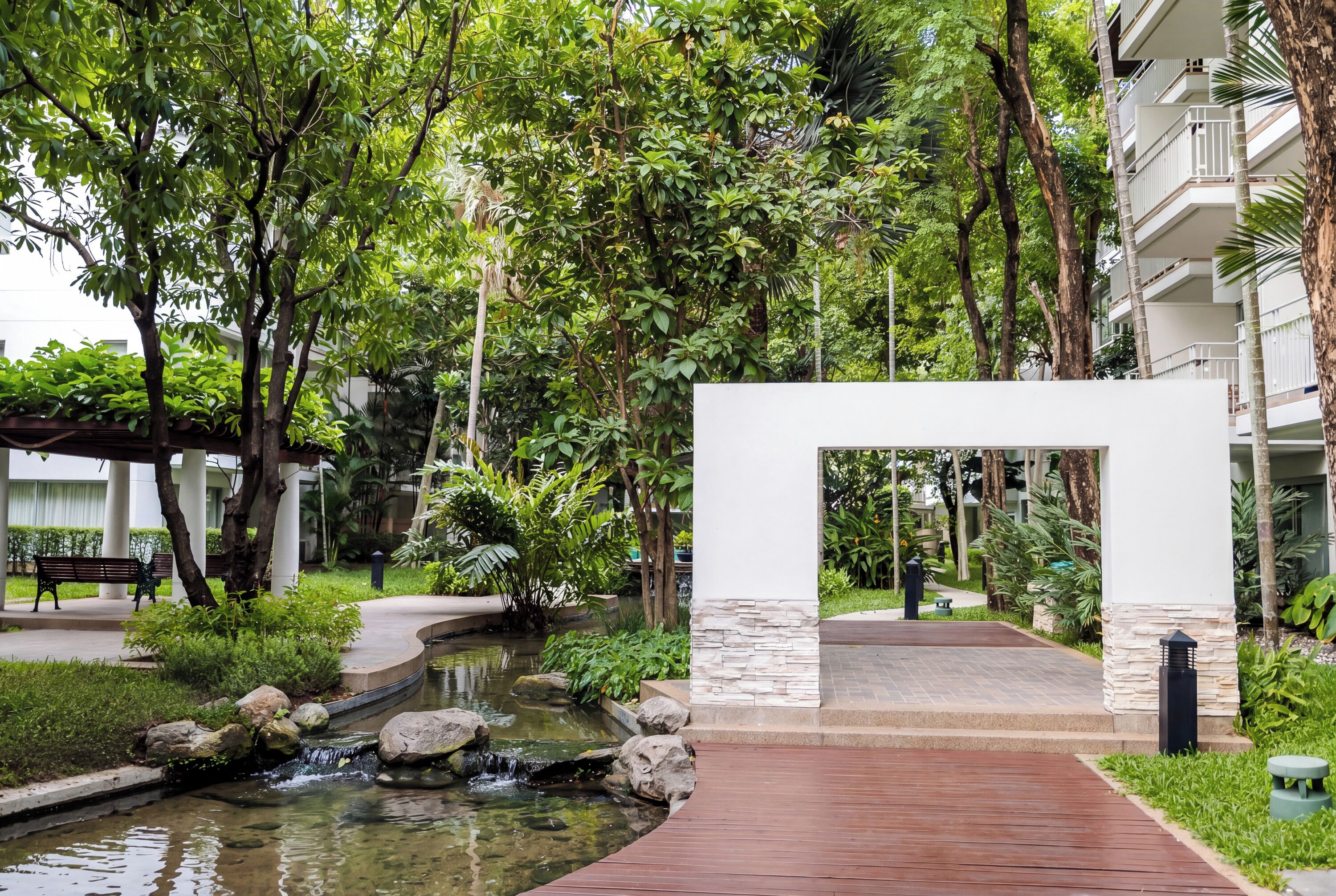 Un jardin aménagé avec un élément aquatique, une structure blanche et un sentier.