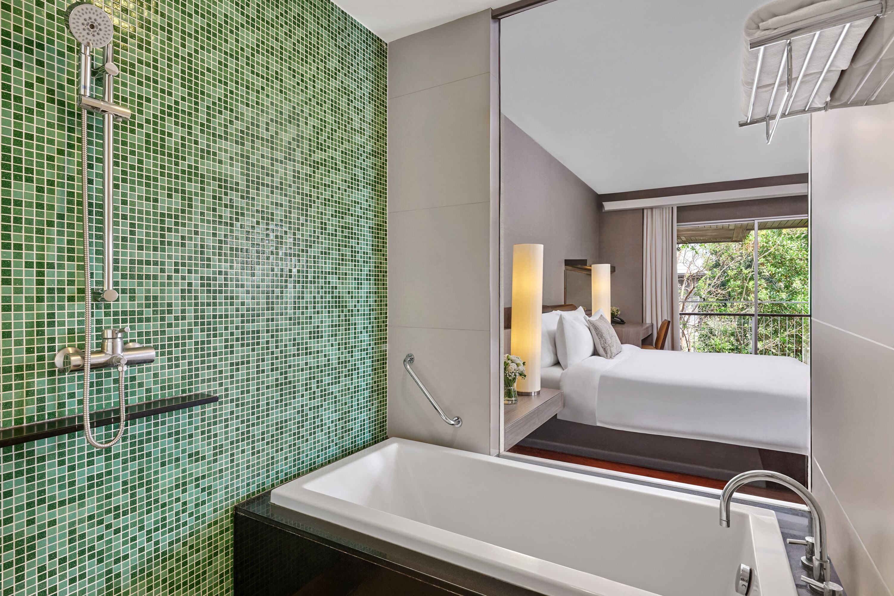 Ein modernes Badezimmer mit einer grünen Mosaikwand, einer Badewanne und einer Dusche.