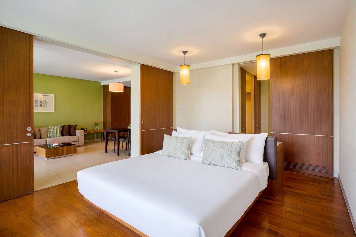 Una habitación de hotel moderna con una cama grande, suelo de madera, un escritorio y una pared verde.