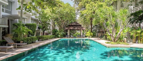 Una piscina al aire libre, sombrillas, sillones reclinables de piscina