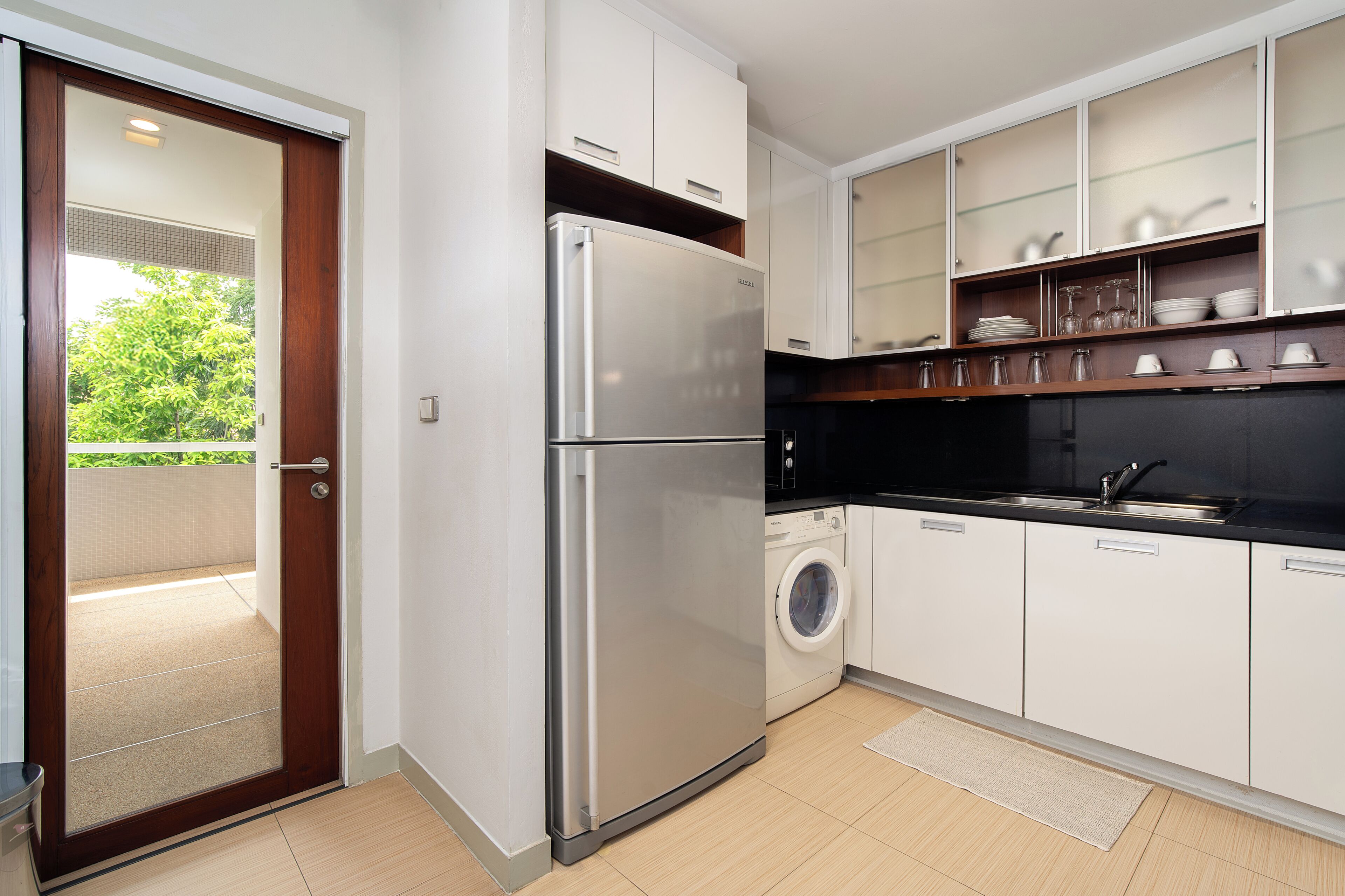 A modern kitchen with a built-in washing machine, a stainless steel refrigerator, and white cabinetry.