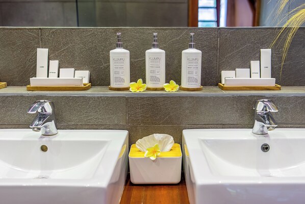 A bathroom with two sinks, a mirror, and shelves displaying toiletries.