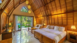 A spacious room with a large bed, a sofa, and a desk. There is a large window and a door leading to an outdoor area. - Klumpu Bali Resort (Denpasar)