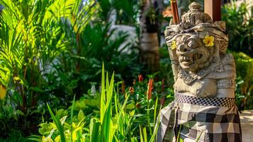 A stone statue with a checkered cloth, surrounded by lush greenery.