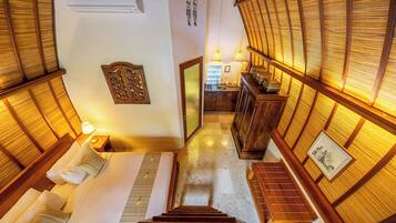 A hotel room with a wooden staircase, a bed, a nightstand, and a view of the kitchen.