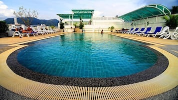 Una piscina al aire libre, sillones reclinables de piscina