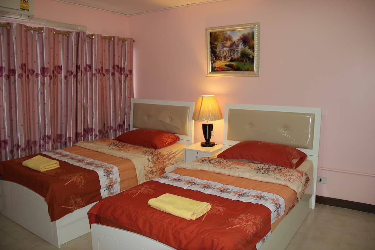 A hotel room with two beds, each with a red and white bedspread, a yellow towel on one bed, and a painting on the wall.