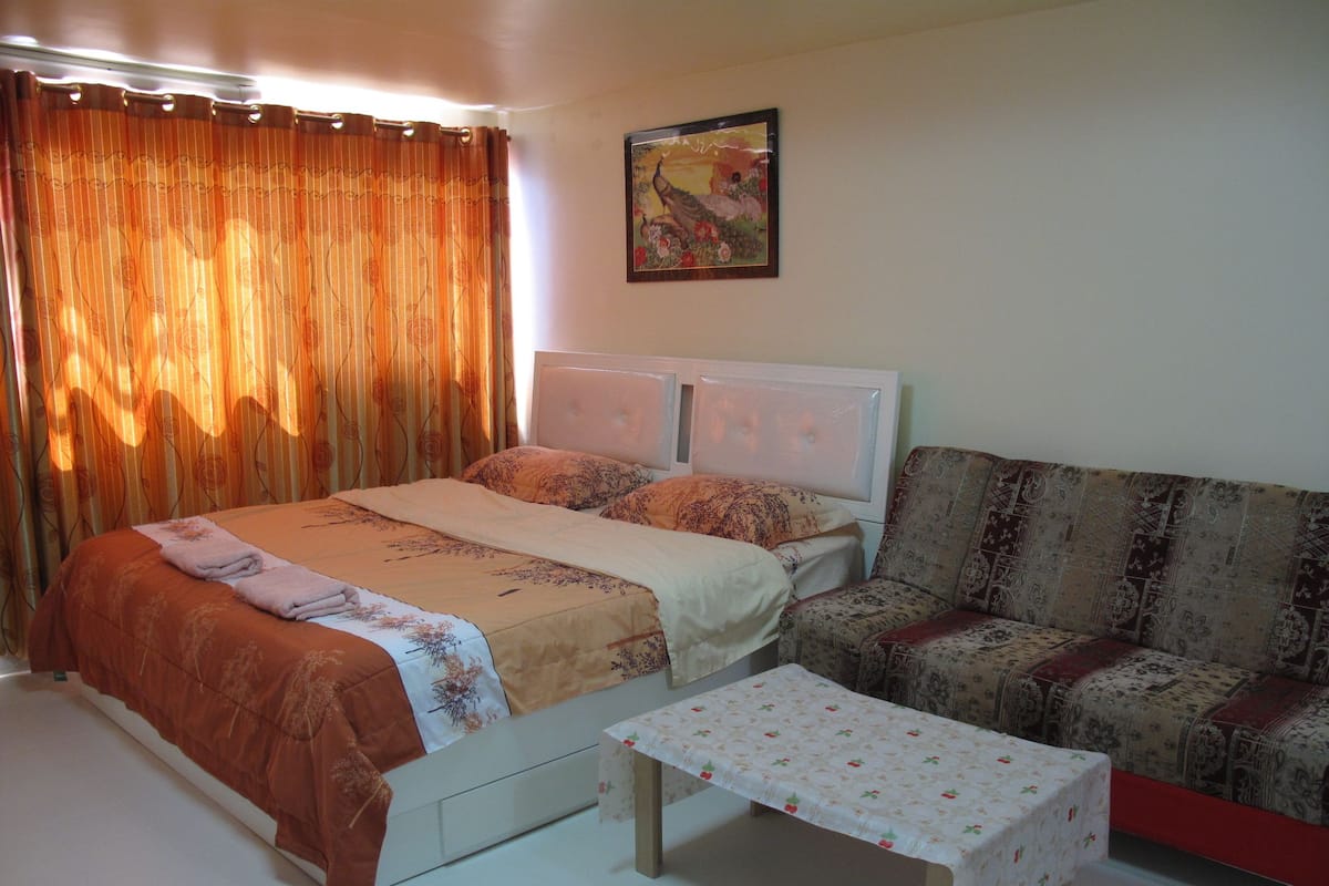 A bedroom with a bed, a sofa, and a small table.