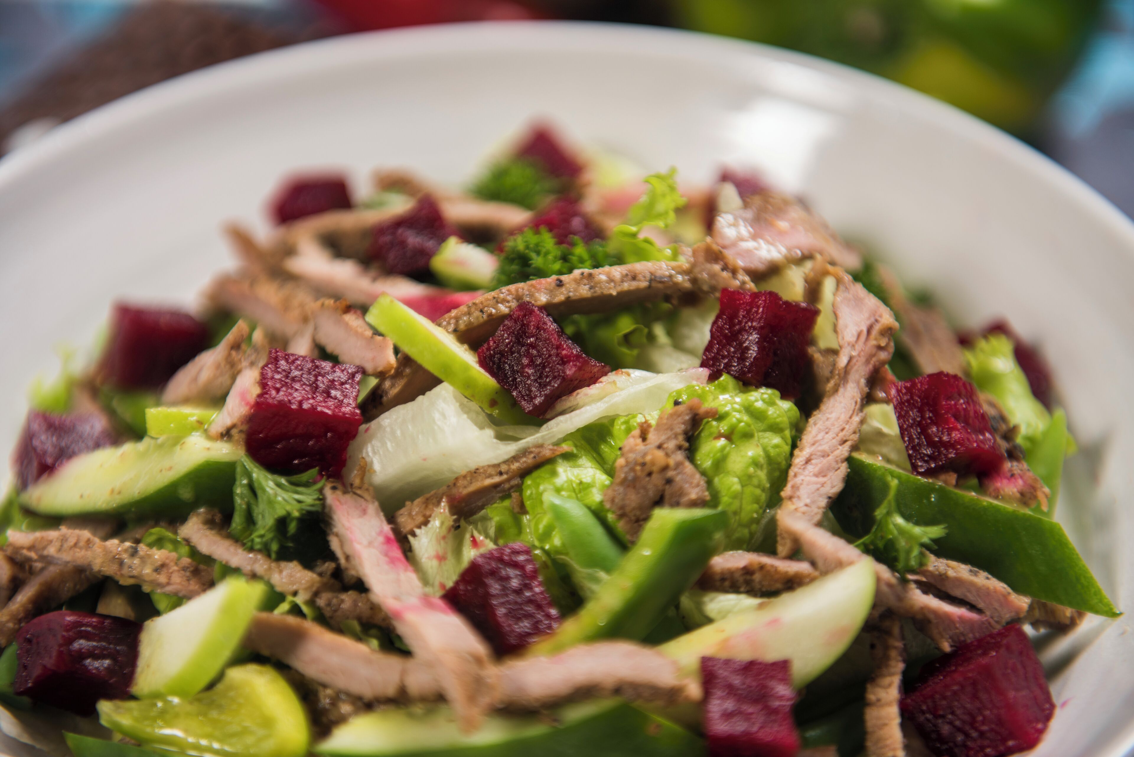 A close-up of a salad with various vegetables and meat.