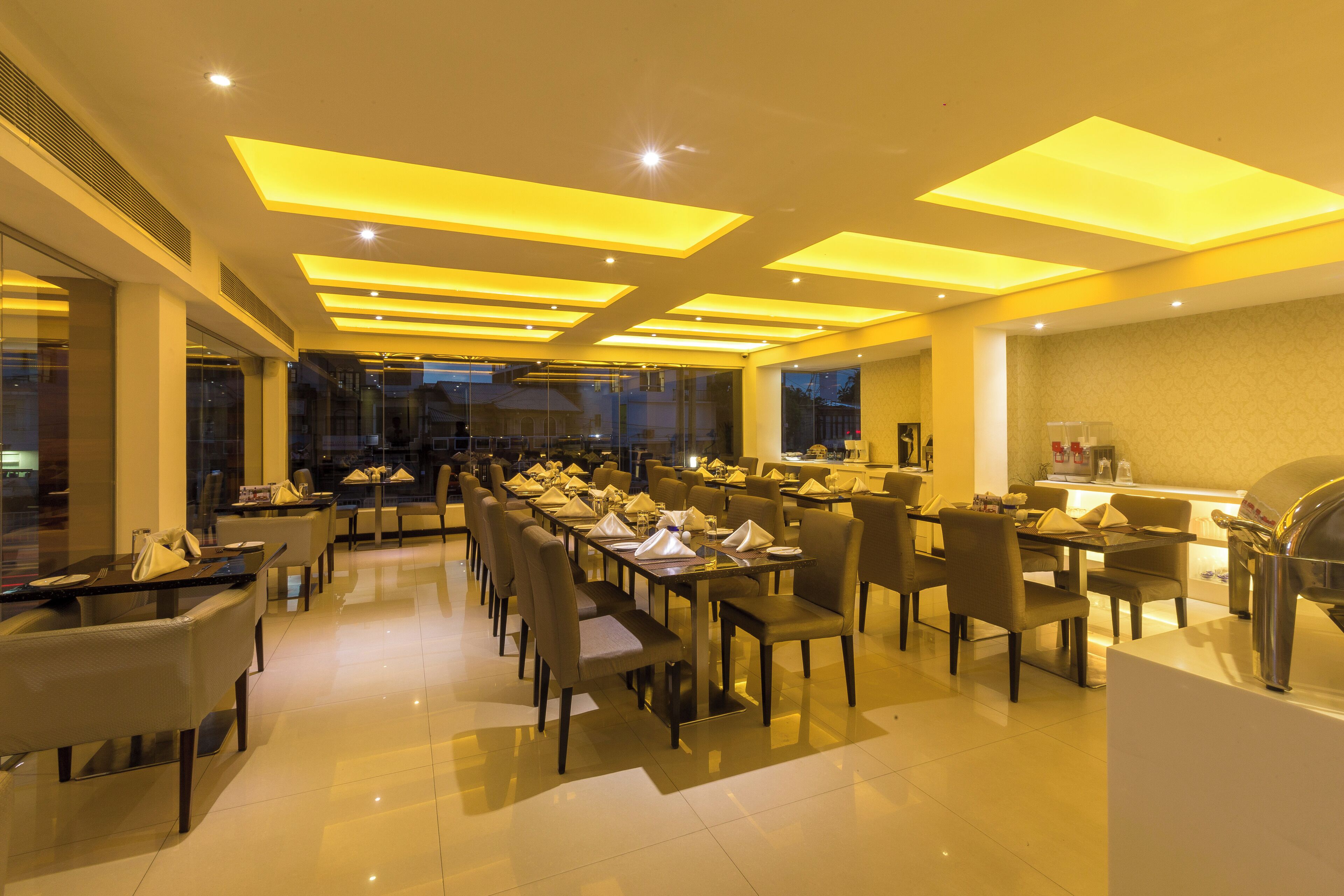 A spacious restaurant with multiple tables and chairs, recessed ceiling lights, and a modern design.