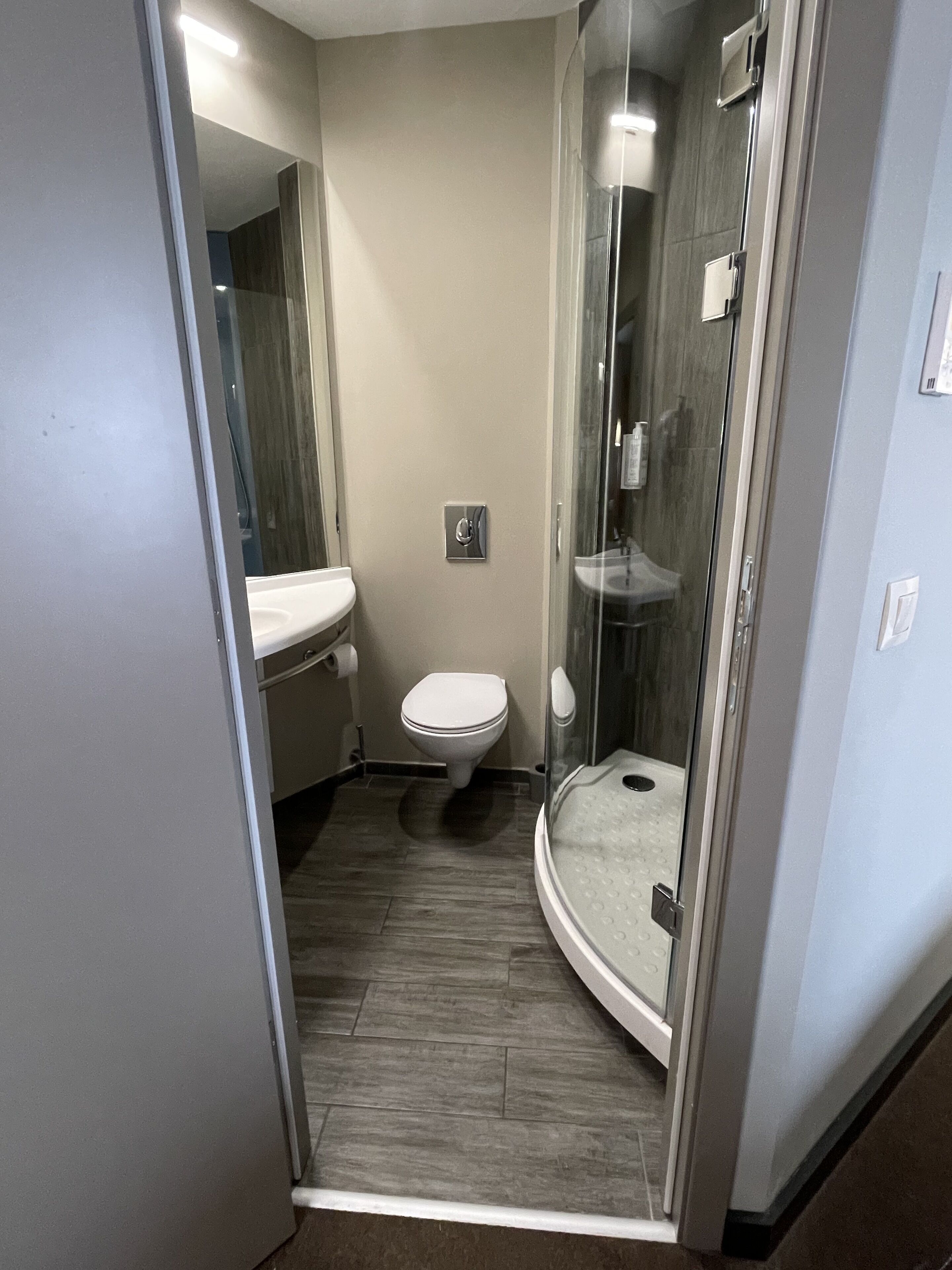 Un baño pequeño con inodoro, cabina de ducha de vidrio y lavamanos.