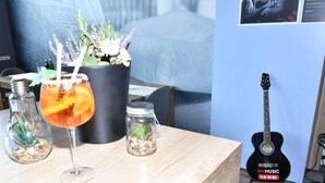 Una mesa de madera con una bebida, una planta en maceta y una guitarra sobre un atril.